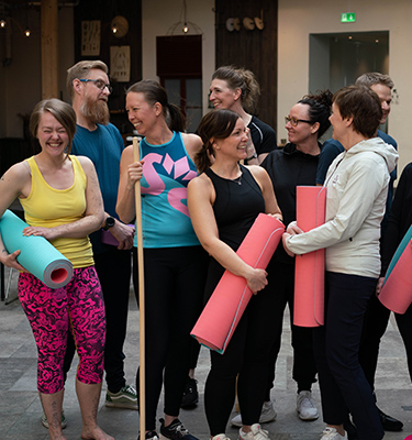 En grupp glada personer med olika träningsredskap som står tillsammans. 