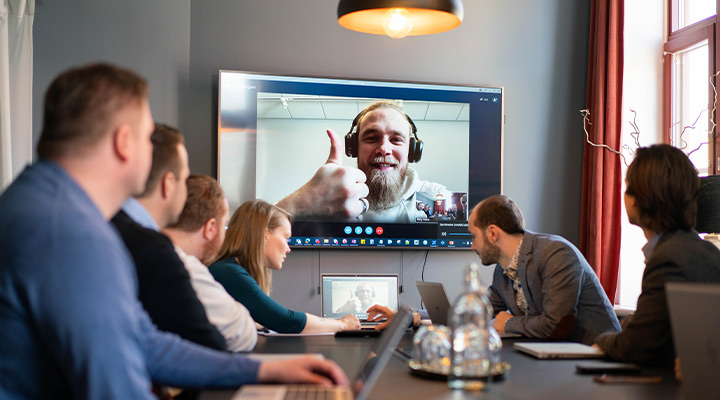 Personer i hybridmöte, person på distans gör tummen upp