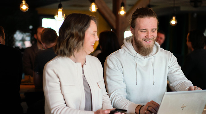 Två personer skrattar vid laptop