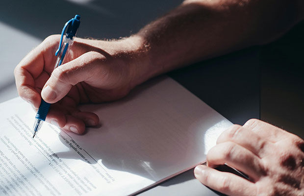 Hand som håller i penna. Skriver under ett avtal. 