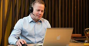 Man med headset arbetar vid en bärbar dator.