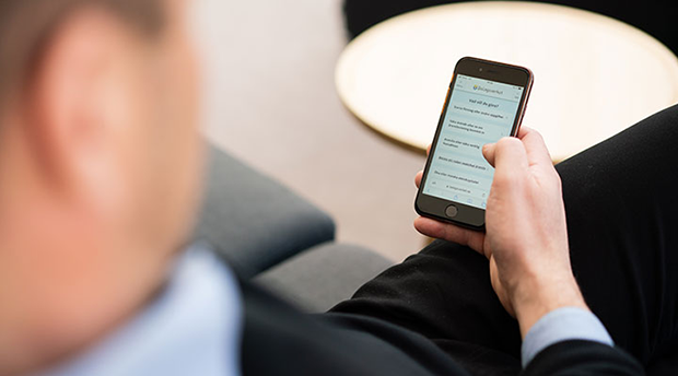 Person som håller en mobiltelefon med Bolagsverkets webbplats öppen på skärmen.