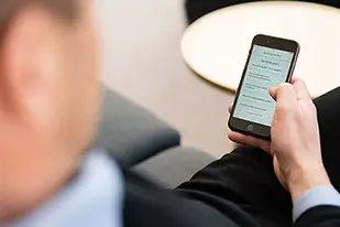 Person som håller en mobiltelefon med Bolagsverkets webbplats öppen på skärmen.