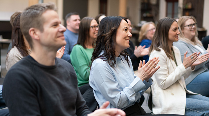 Personer i publik applåderar och ler