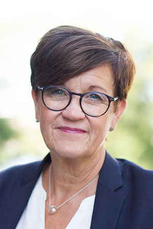 Karin Westling Palm klädd i glasögon, vit blus och en mörkblå kavaj ler mot kameran.