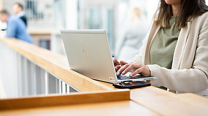 Kvinna sitter vid en laptop som står på ett bord framför henne.