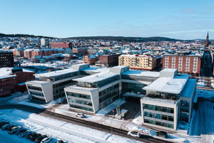 Flygbild över Bolagsverkets kontorsbyggnad i Sundsvall en vinterdag, med snö på taken och stadens bebyggelse i bakgrunden.