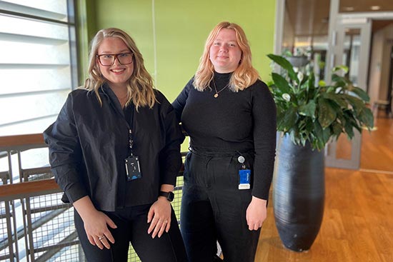 Matilda Davidsson och Agnes Pettersson, klädda i svart står i ett av gångstråken i Bolagsverkets lokaler.