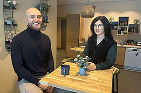 Julia och Marcus sitter vid ett bord med var sin kaffekopp framför sig.