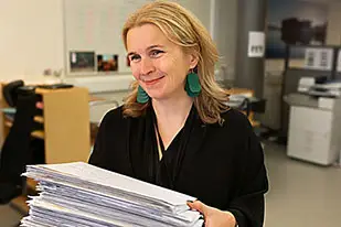 En person står med en stor bunt papper i händerna.