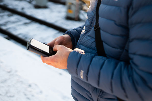 En person i blå jacka skriver på sin mobiltelefon