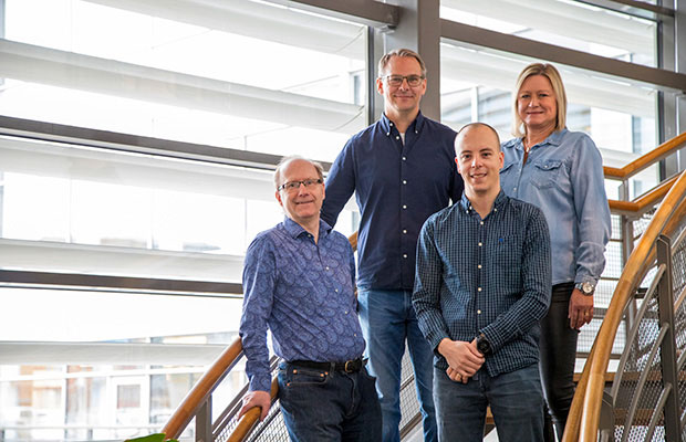 Fyra glada personer står i en trappa i Bolagsverkets lokaler. Alla klädda i blåa nyanser.